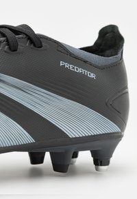 Scarpa da calcio nera con strisce blu chiaro e superficie texturizzata, con colletto imbottito e sei tacchetti per una migliore aderenza. Marchio visibile.