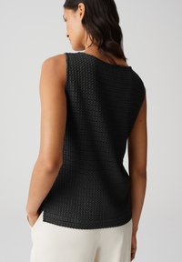 Top senza maniche nero con un design tessuto testurizzato. Presenta un collo rotondo e una vestibilità rilassata, con un orlo leggermente curvo.