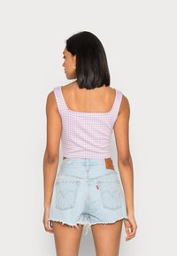 Top cropped de gengibre roxo com decote quadrado, combinado com calções de ganga azul claro com a parte inferior desfiada e bolsos traseiros.