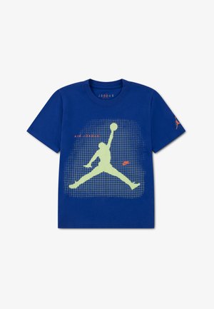 T-shirt bleu à manches courtes présentant une grande silhouette jaune-vert de Jumpman sur une grille, avec des logos rouges "Air Jordan" et Nike sur le devant et la manche.