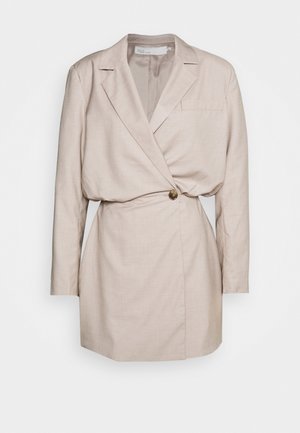 Light beige tailored blazer dress with long sleeves, a single button closure, and a belted waist. Smooth texture and minimalist design.