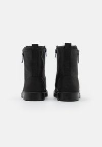Botines negros con combinación de cuero suave y texturizado, cierres de cremallera en los laterales y una suela de goma resistente.