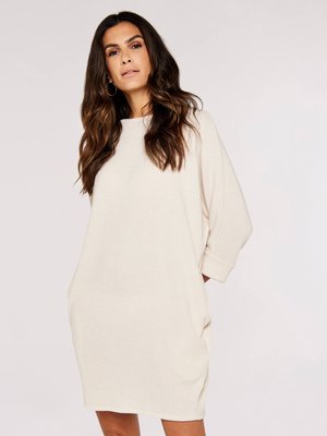 Crème-kleurige geribde jurk met een relaxed fit, voorzien van driekwartmouwen en zijzakken. Zachte textuur, knie-lange ontwerp.