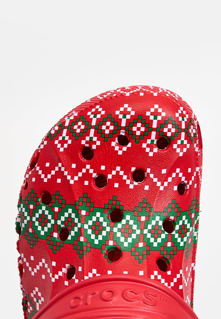 Crocs rossi con un motivo geometrico festivo verde e bianco, dotati di fori di ventilazione e una superficie testurizzata per comfort e traspirabilità.