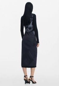Rochie neagră până la genunchi, cu mâneci lungi și un designflorescent. Țesătură netedă cu o siluetă ajustată. Pur și simplu cu sandale negre cu curele.