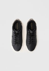 Adidași din piele neagră, cu o finisare netedă, talpă din cauciuc albă și un accent texturat pe călcâi, având șireturi negre.