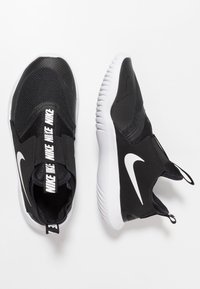 Černé atletické boty s textilním svrškem, elastickými pásky a výrazným bílým logem Nike. Mají bílou podrážku s texturovaným gripem.