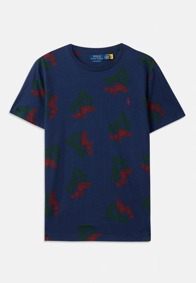 Tamsiai mėlynas medvilninis marškinėlis su kartotiniais žaliais 'P' ir raudonais sparnuotais batų grafikos motyvais, apskritu kaklu, laisvu siluetu ir trumpomis rankovėmis.