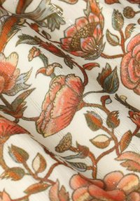 Blumenmusterstoff mit strukturierter weißer Basis. Enthält große rosa und orangefarbene Blumen mit grünen Blättern, akzentuiert von schimmernden Fäden.