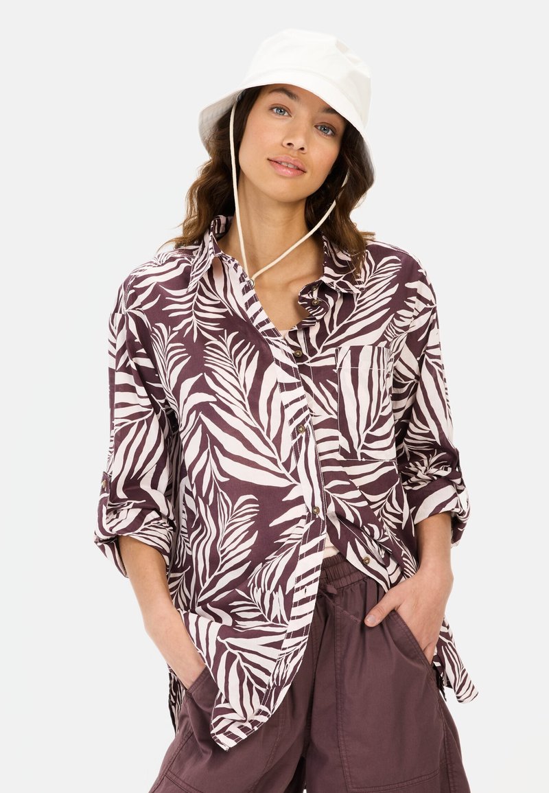 Paars en witte knop-up shirt met een bladpatroon, in een ontspannen pasvorm, lange mouwen en een borstzak, gecombineerd met bruine shorts en een witte bucket hat.