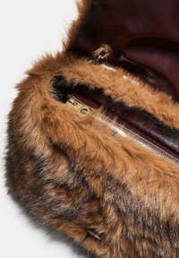 Borsa in pelliccia sintetica marrone con cerniera dorata e interno in pelle marrone, mostrata dall'alto con il flap parzialmente aperto.