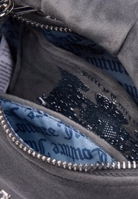 Interno di una borsa in suede grigio con una fodera a motivi blu. Presenta una cerniera argentata e dettagli in rilievo. Il tessuto testurizzato è visibile.