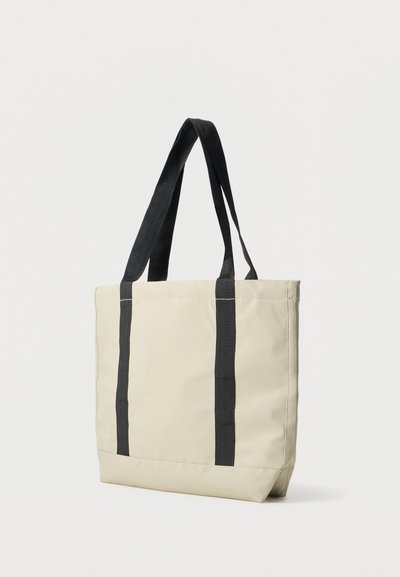 Saco tote bege com alças pretas, formato retangular, feito de um material liso e durável, apresentando riscas verticais pretas nas laterais.