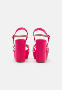 Sandales à talons hauts en daim rose avec un épais talon bloc, une sangle arrière et un design à bout ouvert. Comprend une sangle croisée à l'avant.
