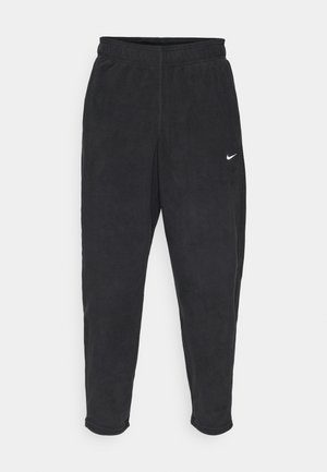 Crne flis trenirke s elastičnim pojasom, suženim nogavicama i malim bijelim Nike logotipom na lijevom butu. Mekana tekstura i ležeran dizajn.