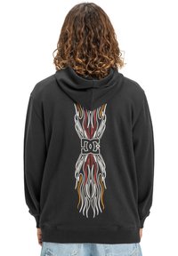 Sudadera negra con capucha que presenta gráficos de llamas coloridas y un logo en la parte trasera. La tela parece suave y tiene un corte holgado.
