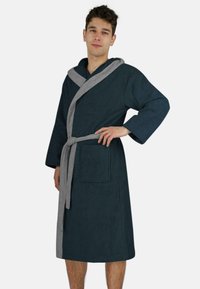 Männerbademantel aus dunkelblauem Frottee mit grauem Kapuzen- und Gürtel. Mit langen Ärmeln und einer Fronttasche. Weicher, strukturierter Stoff.