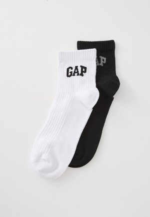 Čarape do gležnja od mješavine pamuka, jedna crna i jedna bijela, s rebrastom teksturom i "GAP" logotipom u kontrastnim bojama na rubu.
