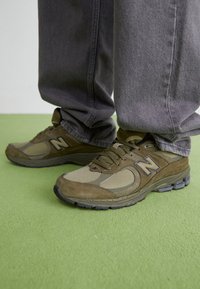 Wojskowozielone buty sportowe wykonane z mieszanki zamszu i siateczki, z dużym logo "N", sznurowane, z teksturowaną podeszwą.