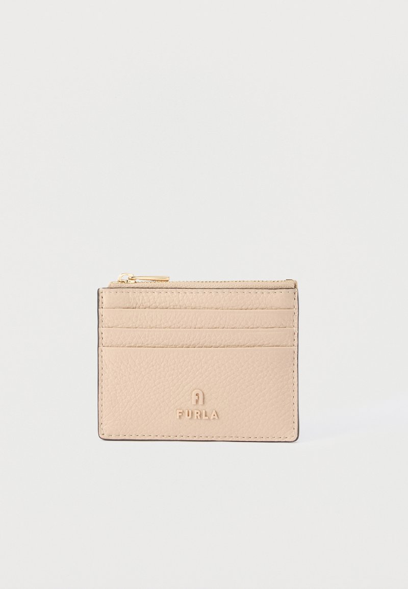 Μπεζ δερμάτινη θήκη καρτών Furla με τέσσερις υποδοχές για κάρτες και τσέπη με φερμουάρ στην κορυφή, επάνω σε απλό λευκό φόντο.