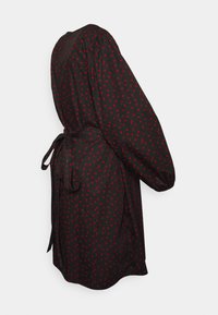 Vestido preto com bolinhas vermelhas, apresentando mangas bufantes longas, um laço na cintura e um corte descontraído. Tecido suave com uma textura lisa.