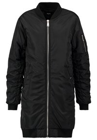 Veste bomber longue noire avec fermeture éclair argentée sur le devant, col, poignets et ourlet côtelés, et une poche zippée sur la manche gauche.
