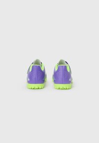 Chaussures de sport violettes avec semelles vertes. Tige texturée avec des trous de ventilation et des accents de marque. Conçues pour une adhérence lors d'activités sportives.