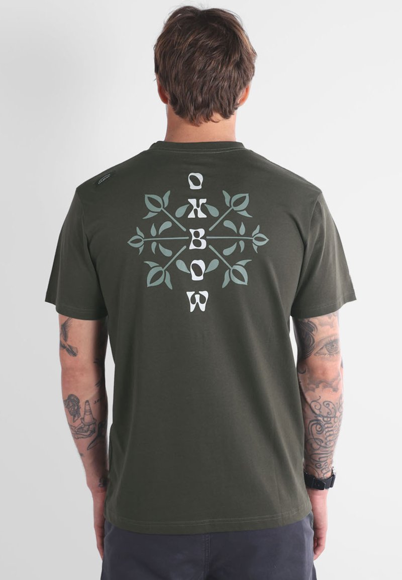 Camiseta de manga corta color verde oliva con un gráfico botánico en blanco y azul claro en la parte posterior, con cuello redondo y textura suave.