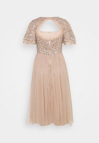 Robe à paillettes avec un corsage chair, des manches courtes et une jupe fluide plissée. Détail du dos en trou de serrure et fermeture éclair.