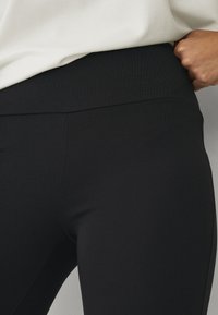 Sorte leggings lavet af strækbart stof med en glat overflade. Høj talje, tætsiddende design, velegnet til aktiv brug eller afslappet brug.