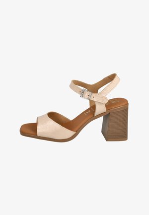 Sandalia de tacón abierta en la parte delantera de color beige con un upper texturizado, una correa en el tobillo que cuenta con una hebilla plateada y un tacón de bloque de madera estriada.