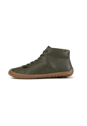 Zapato de piel verde oliva hasta el tobillo con cordones, suela de goma marrón y etiqueta de la marca Camper en la zona del talón.