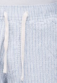 Ύφασμα με γαλάζιες και λευκές ρίγες με κάθετες γραμμές, που διαθέτει ελαστική μέση και λευκά κορδόνια στριφώματος.