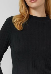 Czarny prążkowany top dzianinowy z wysokim kołnierzem i długimi rękawami. Tekstura zawiera pionowe linie, nadając dopasowany wygląd.