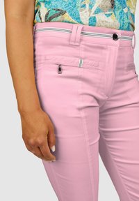 Rosa eng anliegende Hose mit glatter Textur, ausgestattet mit einer Reißverschlusstasche, kontrastierenden Taillenstreifen und einem einzelnen Knopfverschluss.