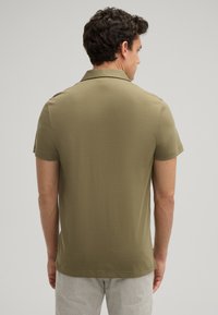 Olijfgroene polo met een zachte stof, voorzien van een klassieke kraag en korte mouwen, met een rechte zoom en subtiele stikdetails.
