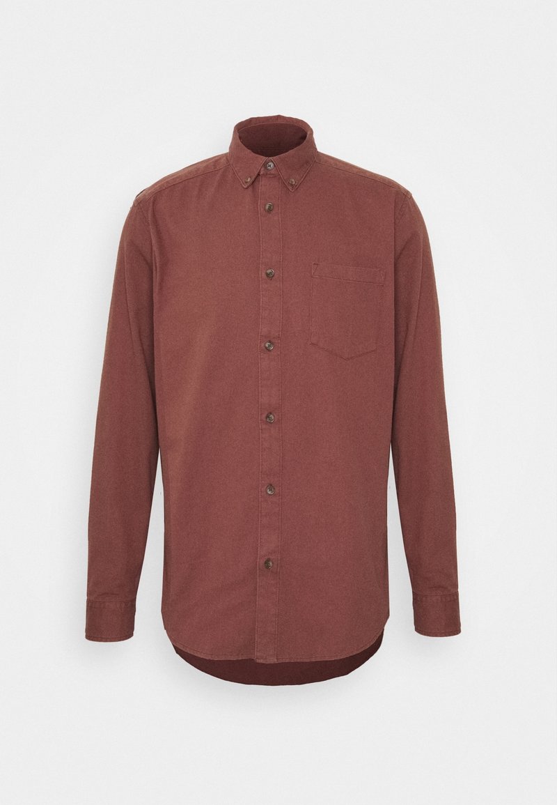 Chemise à manches longues, boutonnée, de couleur rose poudré avec une poche poitrine et un col boutonné, présentée sur fond blanc uni.