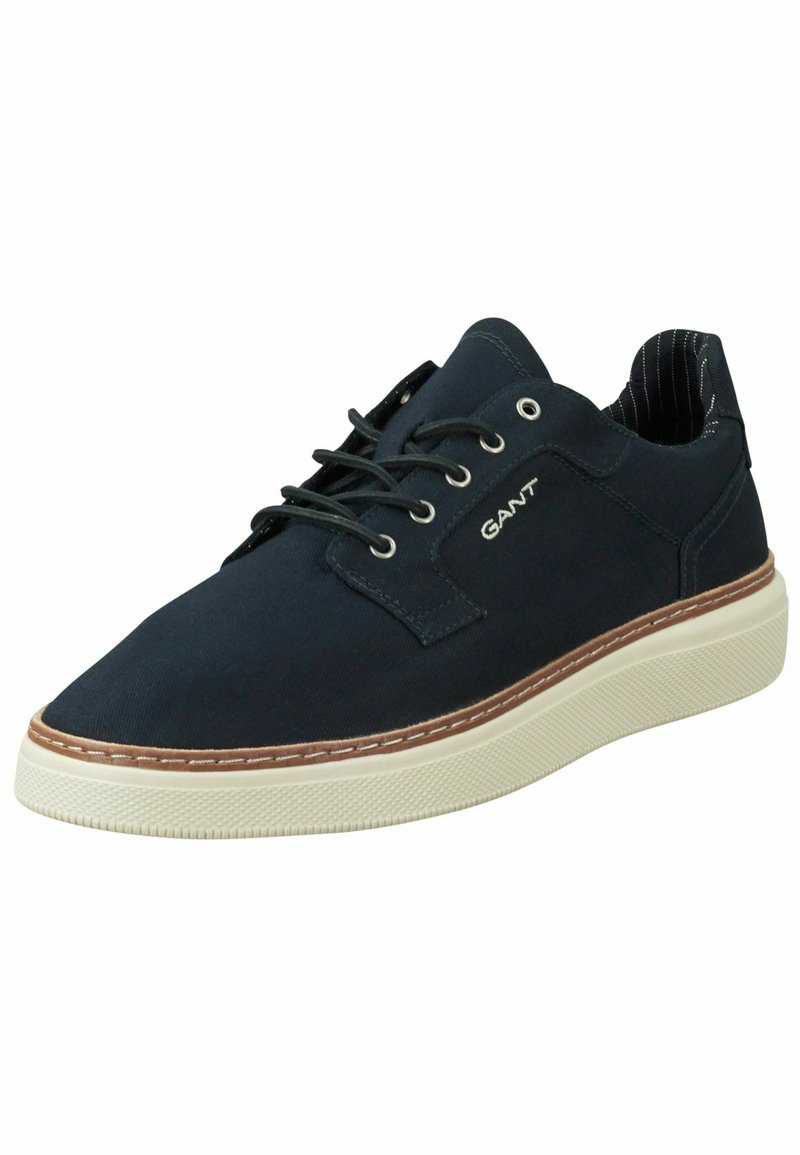 Marineblaue Segeltuch-Sneaker mit weißer Gummisohle, braunen Akzenten in der Naht und schwarz-weißer gestreifter Fütterung. Verfügt über ein Schnürdesign und ein Logo.