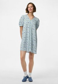 Vestido floral azul claro con mangas cortas abullonadas, escote en V y detalles de botones, que presenta un estampado de pequeñas flores moradas y verdes.