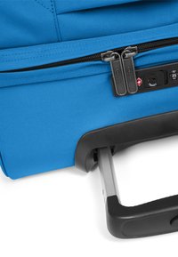 Blauwe koffer op wieltjes met een gestructureerd stoffen oppervlak, dubbele ritssluiting, TSA-slot en intrekbaar handvat voor gemakkelijk transport.