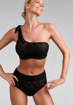 Ensemble bikini noir comprenant un haut asymétrique avec des motifs perforés et un bas taille haute avec des accents géométriques.