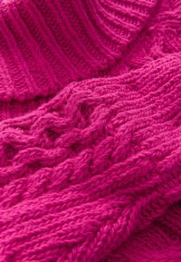 Tissu tricoté rose présentant un motif de câble texturé, avec une épaisseur variable et une finition douce et duveteuse. Inclut des sections côtelées.