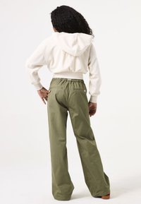 Haut à capuche côtelé crème avec une capuche au dos, associé à un pantalon large vert olive doté d'une taille élastique et de poches arrière.