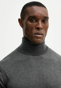 Maglione dolcevita grigio realizzato in tessuto a maglia fine, caratterizzato da un colletto alto e una texture liscia e uniforme, esposto su uno sfondo neutro.