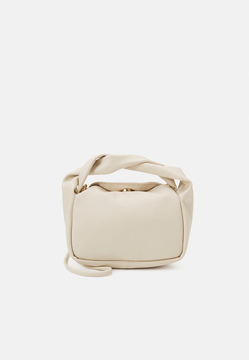 Petit sac à main beige doux avec une bandoulière torsadée et une forme rectangulaire arrondie sur un fond uni.