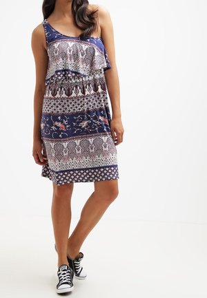 Mouwloze marineblauwe jurk met gelaagde ruches en gemixte patronen van bloemen- en geometrische ontwerpen in contrasterende kleuren.