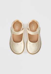 Heledbeezid Mary Jane kingad, millel on sile nahataoline viimistlus, dekoratiivsed aukudega detailid varvaste piirkonnas ning kinnituse jaoks pandla kaas. Pehme, polsterdatud tallaosa.