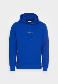 Koningsblauwe hoodie met voorzakken, trekkoorden aan de kap en het "Calvin Klein"-logo in het midden van de borst.