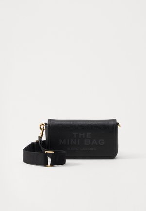 Sac mini en cuir noir avec une finition texturée. Il dispose de quincaillerie dorée, d'une bandoulière détachable et d'un logo en relief sur le devant.