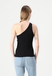 Black, fitted tank top with an asymmetrical one-shoulder design. Made of ribbed fabric. Back showcases smooth texture and clean seams.